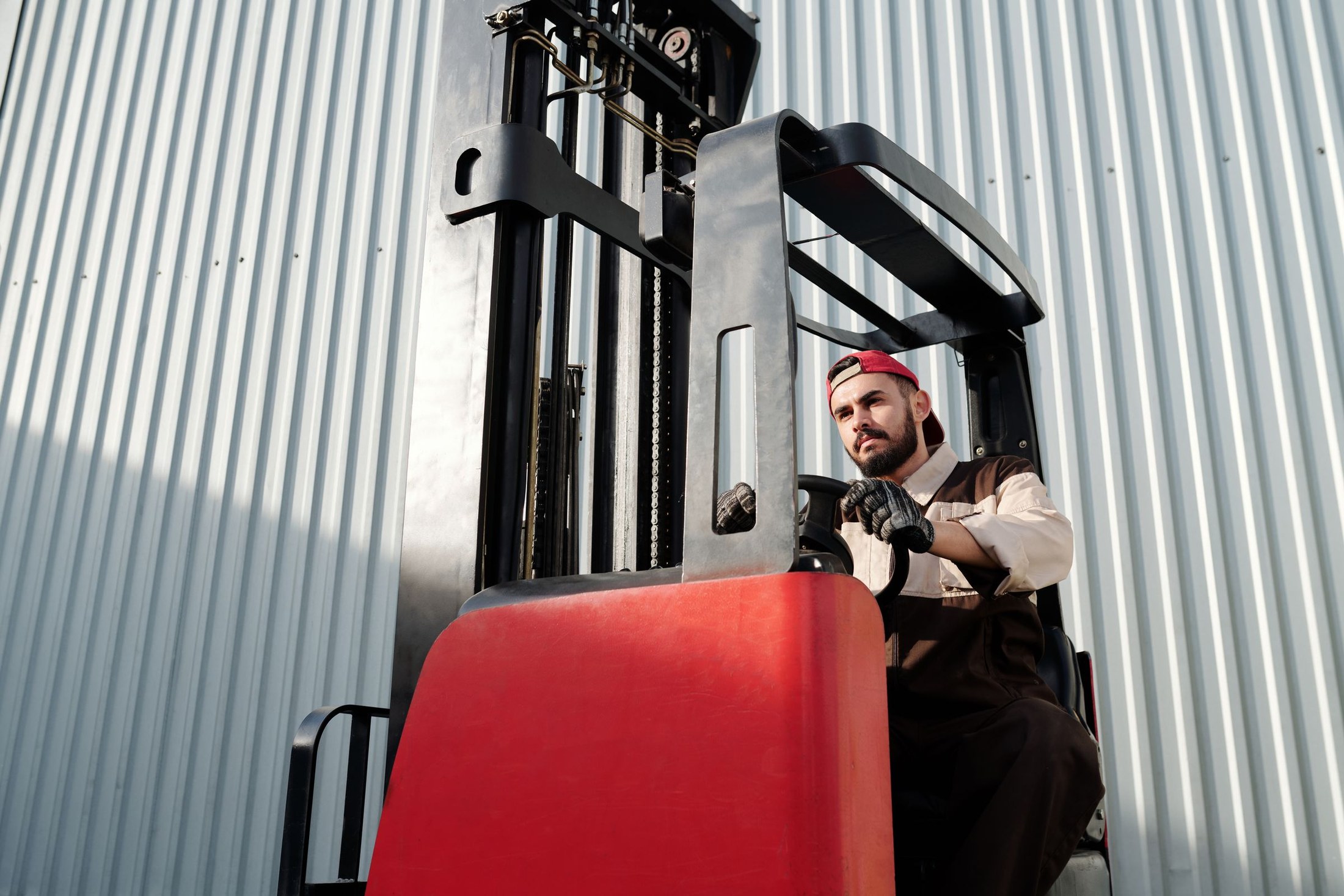 Operator at the controls of a forklift beside a warehouse wall